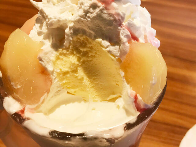 その下には、びくドン名物の激うまソフトクリームがたっぷりと。だんだんとそれぞれのアイスやソースと具材が混ざり合って、たまらない美味しさになっていく。【びっくりドンキーのジョッキパフェ（ピーチ）】