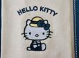 夏らしい麦わら帽子を被り、爽やかなブルーのボーダーTシャツとオーバーオールを着用したキティちゃんがなんともキュート!