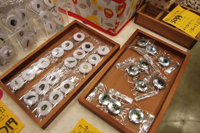 「lakkasei」のてんとう虫缶バッチと、メタリックな甲虫の缶バッチ。