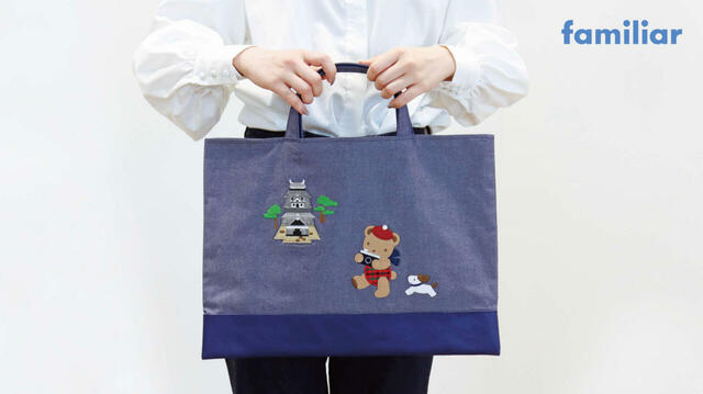 【ファミリア「デニムバッグ」】サイズは約縦32×横43cm。松江城を背景に、クマちゃんとワンちゃんが旅行を楽しんでいる様子が描かれています♪