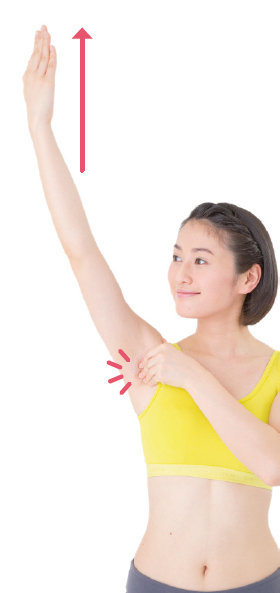 肩こり・首こりに効く気リンパその１／わきの下押しで腕を上げ下げ（左右10回ずつ）／1. 片方の手を上げる。上げた手のわきの下に、もう片方の手を差し込むように入れ、わきの手前をつかむ。