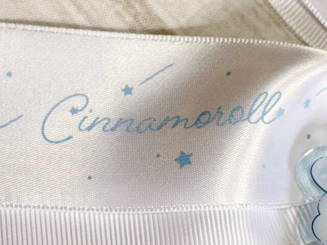 サテン調リボンには、淡いブルーで「Cinnamoroll」のロゴプリント入り