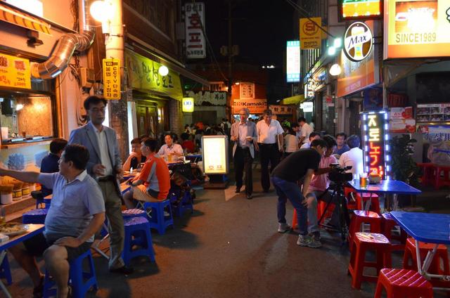 【ソウル乙支路3街】2014年のノガリ横丁。奥がレンガ倉庫、手前左の黄色い看板が「満船ＨＯＦ」。右のSINCE1989の看板がミュンヘン。右手前にテレビ局のカメラが