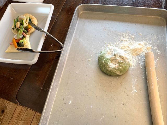 ほうれん草を練り込んだピザ生地を綿棒で伸ばす