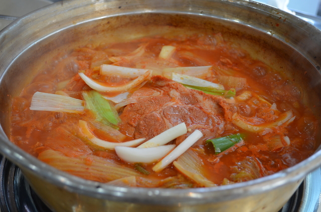 専門店のキムチチゲ。洗面器のような鍋に入っている。鍋が凸凹なのはレトロ感を出すための演出