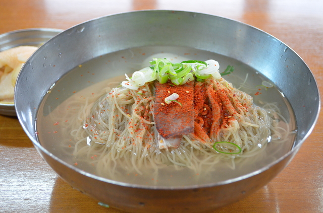 「筆洞麺屋」のムル冷麺は10000ウォン。スープのコクが印象的。店は忠武路駅1番から地上に出て、そのまま歩道を進み、新韓銀行の角を右折、しばらく進んでGS25（コンビニ）がある交差点を左折し、五差路に出ると左手に見えるレンガの建物