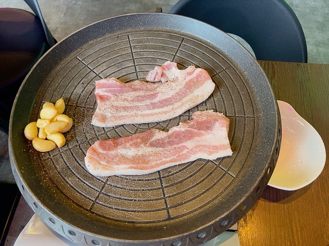 【韓国大衆酒場 ラッキーソウル 渋谷文化村通り店 実食レポート】注文して5分ほどで生の肉が2枚とニンニクの載った鉄板がコンロの上に置かれました