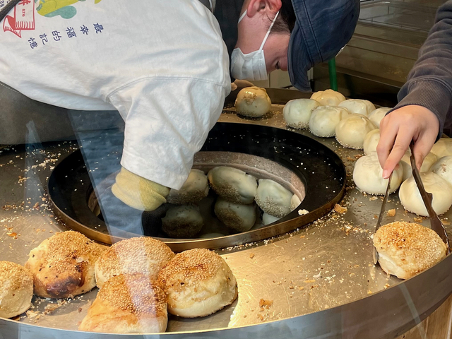 【台湾老劉胡椒餅 吉祥寺店】取り出した胡椒餅を別のスタッフがトングでつかみ、紙袋へ移し、包んでいく