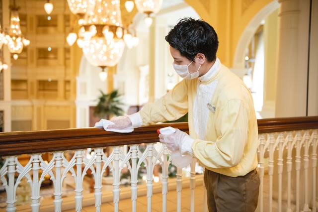 キャストが館内の手すりを清掃・消毒している様子