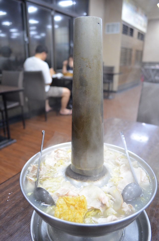 見上げるような煙突が付きだした鍋にたっぷりの酸白菜と豚肉が入る