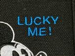 ミッキーのお顔の上には鮮やかなブルーカラーで「LUCKY ME！」のロゴ刺繍入り。ブラック地に映えるアクセントになっています