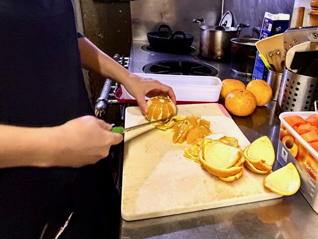 【カタネカフェ】オレンジをカット中の智子さん。皮も余すことなく使い切るそうです