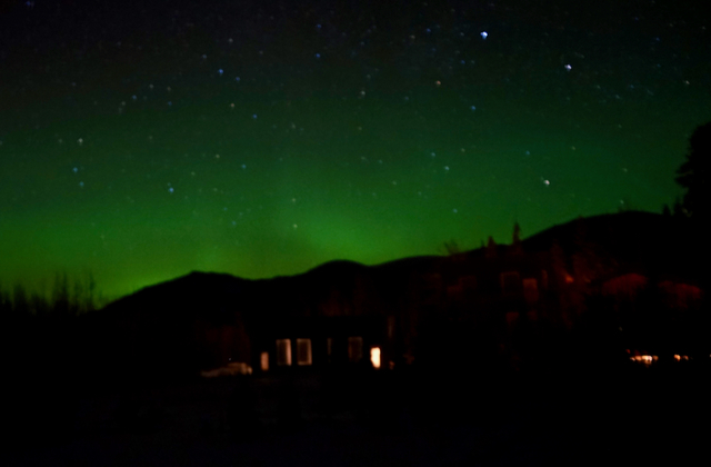 コテージから漏れる灯りの奥に、緑色のカーテンが揺れる。