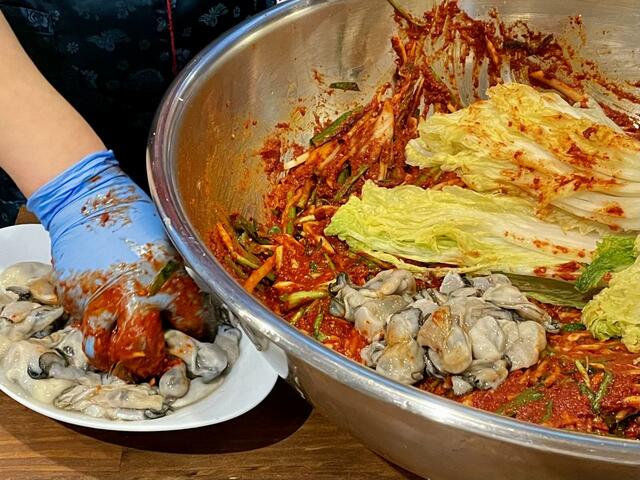 【釜めし 大統領】牡蠣を香味野菜が入ったヤンニョムに混ぜ、白菜につめていく