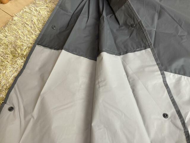 【スリーコインズ バイカラーレインポンチョ】、袖には2つのスナップボタンがあり、風に煽られて袖が広がるのを防ぐ