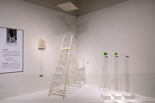 中央の作品《Ceiling Painting（天井の絵）》は、小さな文字で書かれた「YES」 の文字を脚立を登って虫眼鏡で見るという作品。ジョンはこの“YES”という 肯定的な言葉に、温かい気持ちになったという