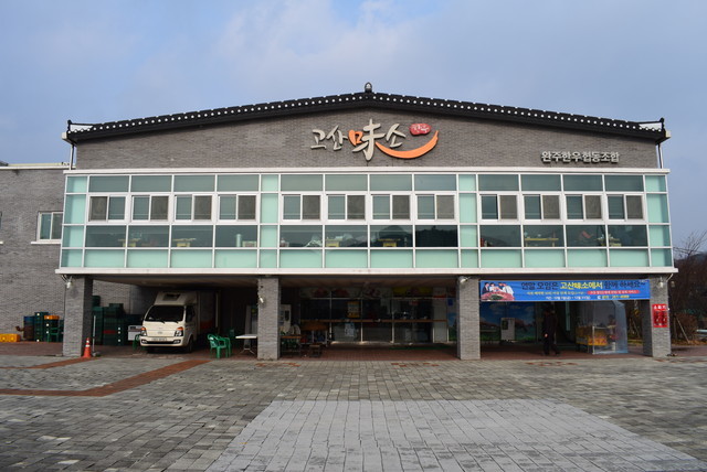 店名のコサンは地名の高山の韓国語読み、ミソは味の韓国語読みのミ＋韓国固有語で牛を表すソと、ミソ（微笑の韓国語読み）をかけている。全州の東部市場の停留所から535番のバス乗車、高山農協の停留所下車。そこから徒歩15分