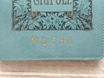 アートの下部には「MUCHA」のゴールドの箔押しロゴ入り