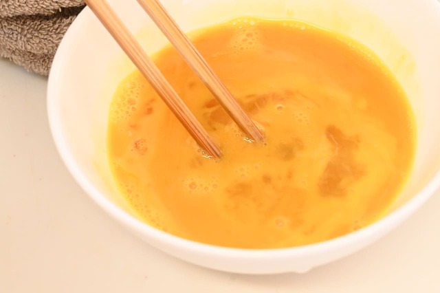 【もち麦卵焼き】【もち麦卵焼き】卵焼き器を中火で熱し、サラダ油を入れて卵液1/3量を流し入れ、下半分に明太子を並べ入れて包む