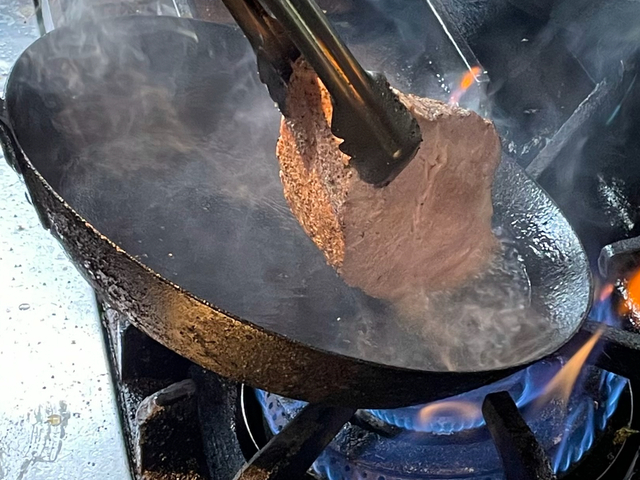 【マロリーポークステーキ】芯まで火が入っている肉の塊をフライパンでソテーする