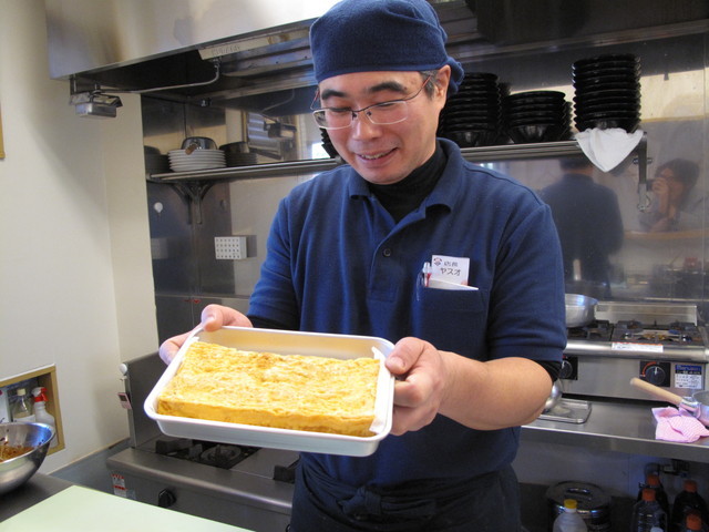 麺や小僧：自慢のだし巻きたまごを持つ店長
