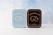 左側：期間限定 クルミッ子10個入（缶）ペールブルー／右側：定番商品 クルミッ子10個入（缶）茶色