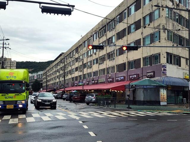 弘済駅をあとにするマウルバス後部座席からの風景。右手がユジン果物卸売商店街の建物
