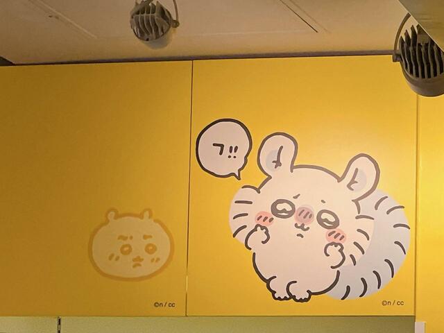 店内上部の壁。ちいかわの真似をするモモンガを横目で見るちいかわの表情に注目です！