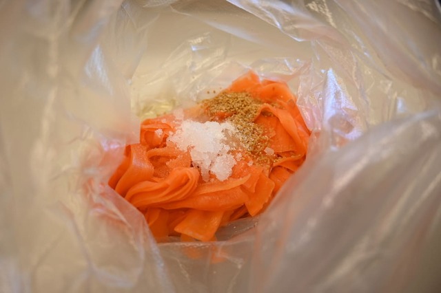 【キャロットラぺの作り方】３．酢、オリーブオイル、砂糖、コンソメを入れ、袋の上から手で揉んでできあがり。