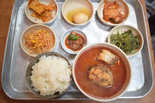 『スリョンチプ』のトンテチゲ定食4000ウォン。前列左から大盛りごはんとトンテチゲ。中列左から豆モヤシのナムル、貝の塩辛、海草のナムル。後列左からオデン（魚のすり身）、茹で卵、ハクサイキムチ