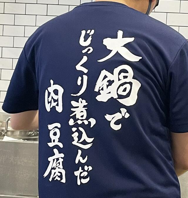 スタッフのユニフォームに書かれた「肉めし岡もと」のメッセージ