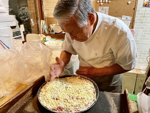 【トニーズピザ】トマトやベーコンなどをあしらった生地に３種類のチーズを盛りつける