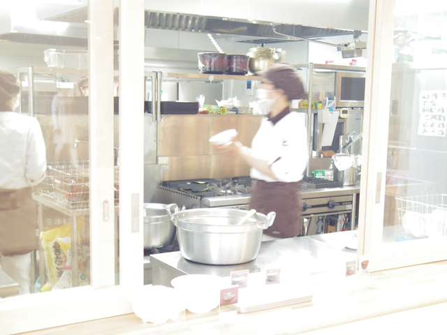 ガラス張りのキッチンからは、素敵なビストロウェアに身を包んだ調理スタッフが
