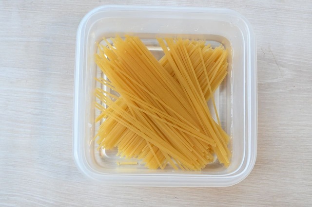 【フレッシュトマトとベーコンのパスタ】耐熱容器に水を入れ、パスタを半分に折り入れます