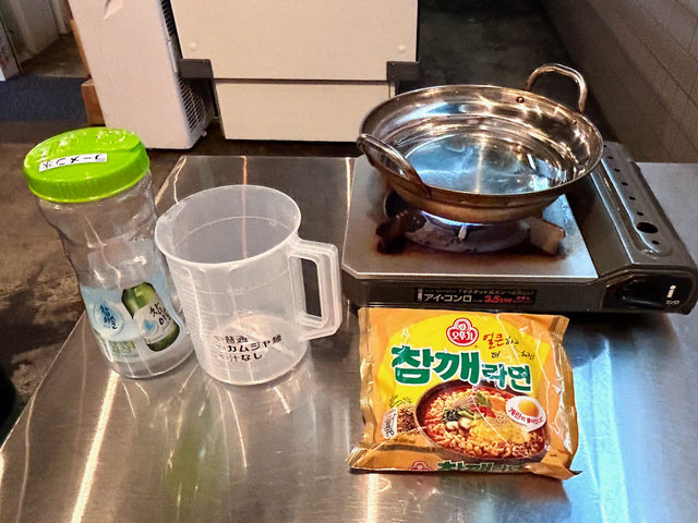 【モナミ食堂】ポットの水をカップではかり、適量を鍋に入れ、鍋で沸かしてラーメンを作ります