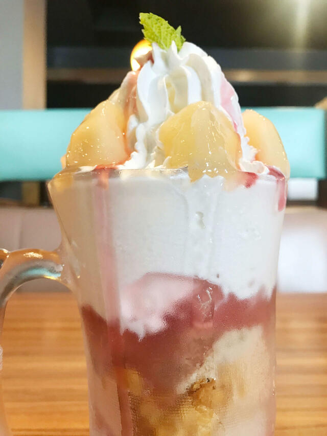 上部には桃の果肉や、ホイップクリーム、ソフトクリームらしき層が見えます。【びっくりドンキーのジョッキパフェ（ピーチ）】