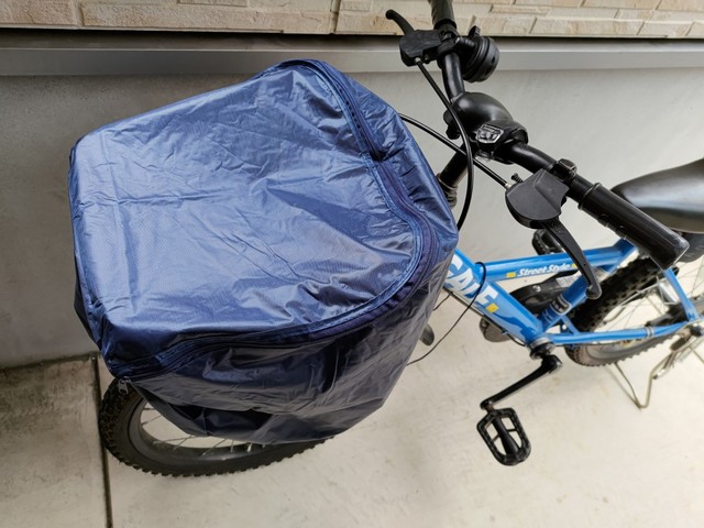 【キャンドゥ】自転車前カゴカバー（PVCコーティング）の使用イメージ。奥行28cm×幅36cm×高さ32cmのサイズ内であればすっぽりと覆ってくれます。