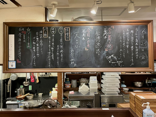 【トーキョーアジフライ】カウンターの上に掲げられた黒板。アジや米の産地など、ご主人の宮木さんがチョークでしたためた文字やアジのイラストがかかれている