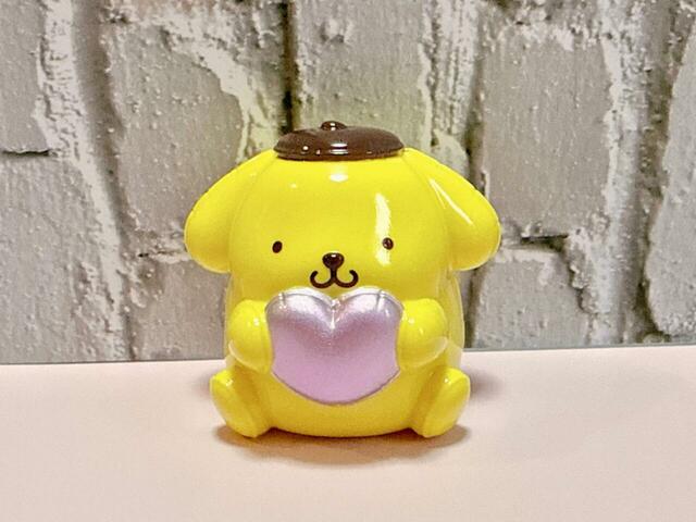 ポムポムプリンは、パールピンクのハートをぎゅっと抱えたデザイン