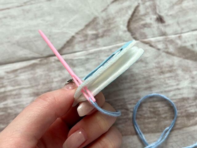 表側の裏面からプラスチック針を左下の穴に通します