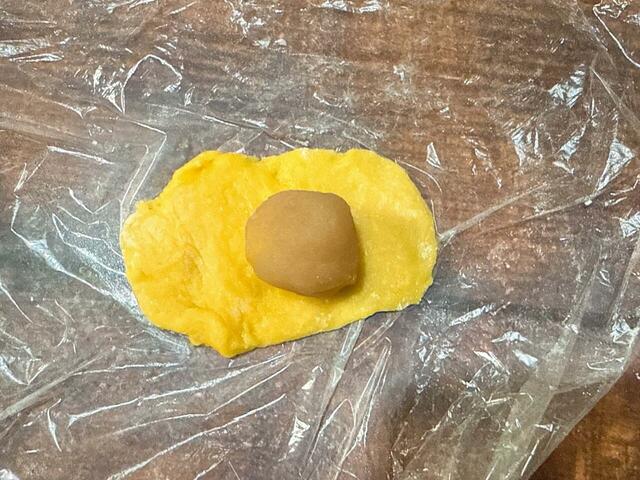 手に打ち粉をしてから、丸めた(5)を平らにし、(3)を包みます