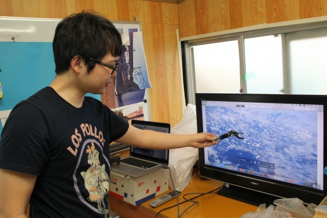 ワッヘンフィルムスタジオ／ハイパー人形劇の作り方を説明する飯塚さん。画面に背景となる景色を映し出し、その前で人形を操作する