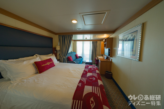 大きなベッドとソファーの奥にベランダがあるベランダ付きのステートルーム