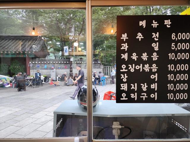 移転前は、飲み代だけ払えば食べ放題のつまみが数種類並んでいるだけだったが、新店舗では一品メニューもできた。上からニラのチヂミ6000ウォン、果物5000ウォン、豚肉炒め、イカ炒め、ヌタウナギ、豚カルビ、鴨肉焼き（いずれも1万ウォン）