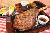 180gの「ランプステーキ」（後方）と比べると、「トマホークステーキ」は約6倍の大きさ！