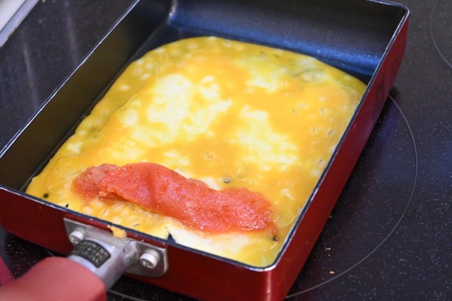 【もち麦卵焼き】卵焼き器を中火で熱し、サラダ油を入れて卵液1/3量を流し入れ、下半分に明太子を並べ入れて包む