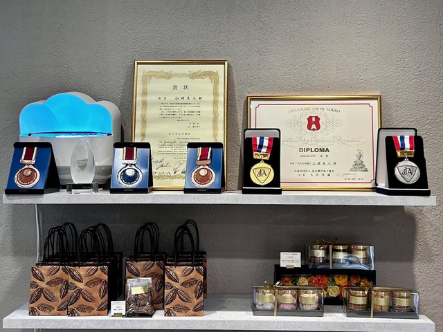 【Atelier Y】「2015年ジャパンケーキ賞 ピエスアーティスティック部門 金賞」、「2016 年ジャパンケーキ賞 味と技のピエスモンテ部門 銀賞」などの受賞歴を物語る賞状やメダルが飾ってあります