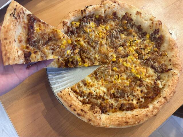 【ロピア テリヤキチキンピザ】こんがり焼けたピザを手に持つと、具材の重みでずっしり。コスパ最強のごちそうピザ、ここに爆誕！