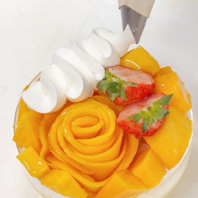 仕上げにもうひと押しの「追い生クリーム」、苺も添える。【お菓子のたいようのビッグパフェ3種】