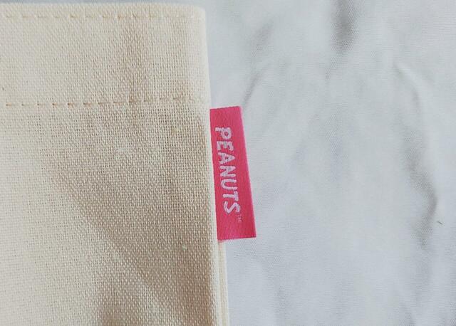 「PEANUTS」のピンクカラーのロゴタグがついています